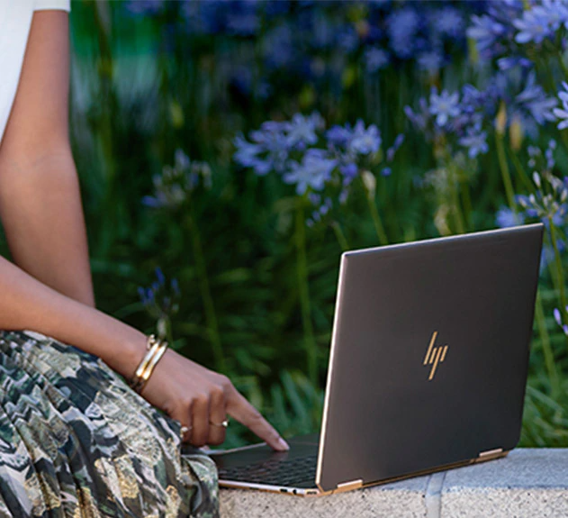 Image latérale d’un ordinateur portable sur un mur touché par une femme - Ordinateur portable convertible puissant HP Spectre x360