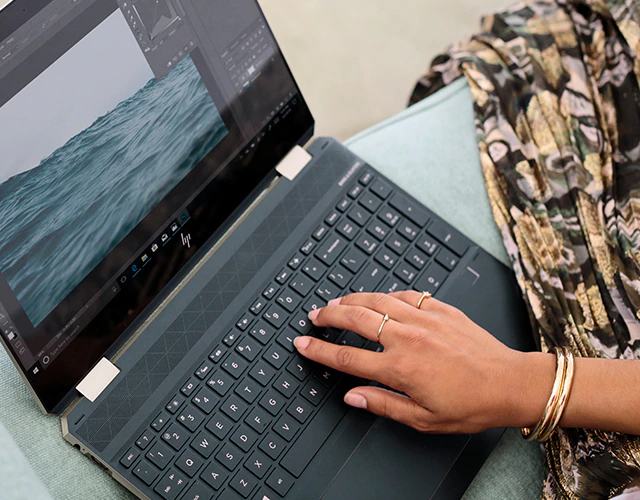 Ordinateur portable ouvert sur une table avec une main sur le clavier - Ordinateur portable convertible puissant HP Spectre x360