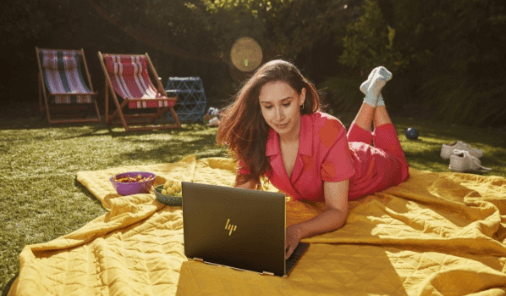 Woman in her garden, typing on her HP spectre x360 14