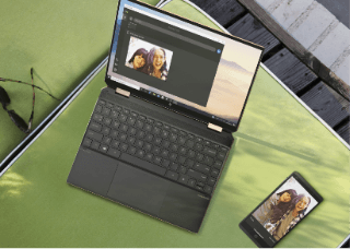 A laptop and a mobile phone laying on a green balcony sunbed